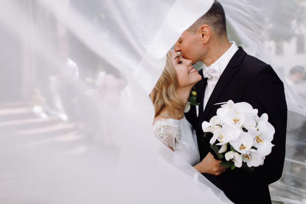 groom in black tuxedo hugs tender stunning bride while they stan