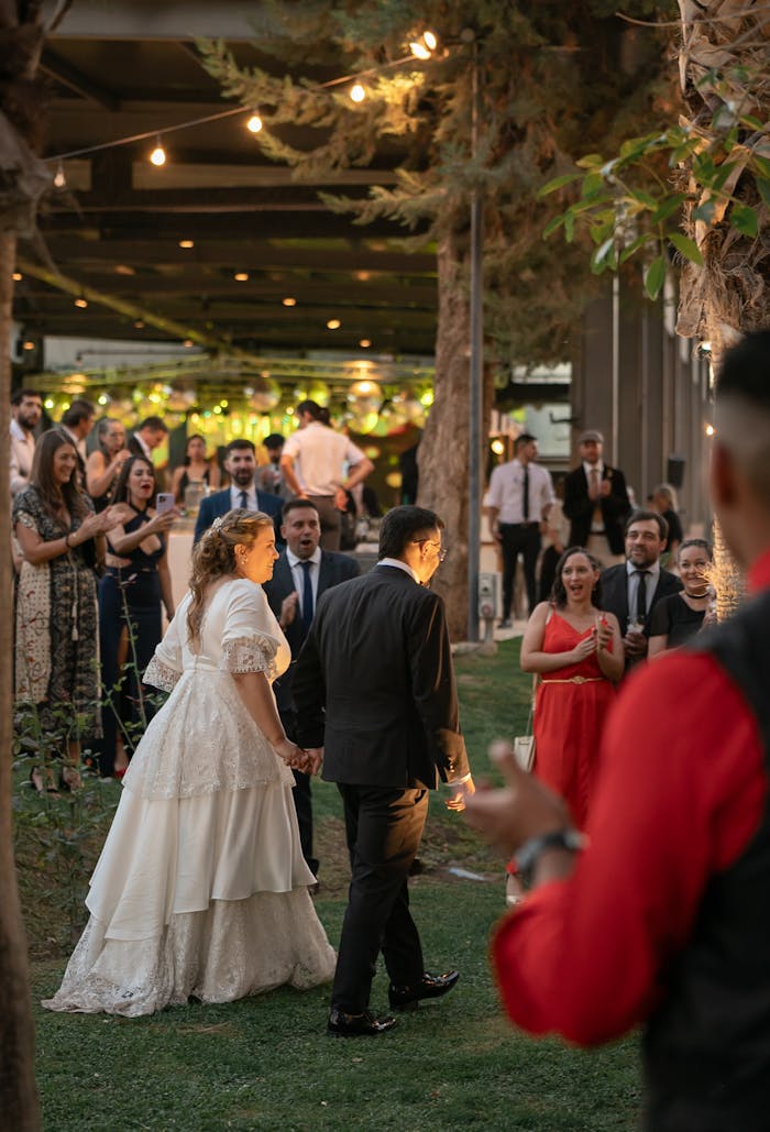 Bride and groom walking hand-in-hand among guests during an outdoor wedding reception in Mendoza, Argentina.